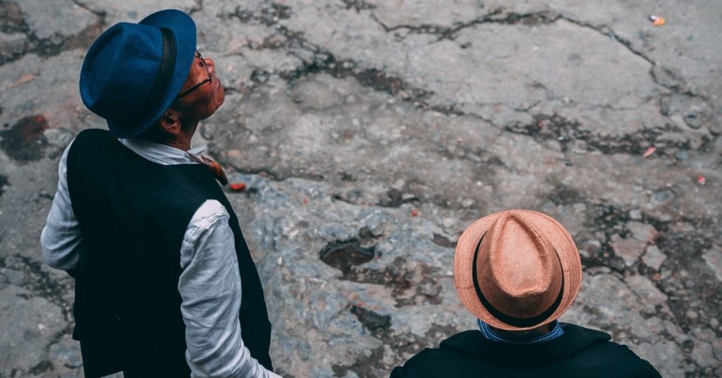 photo shows two men of colour wearing wide brimmed hats looking up
